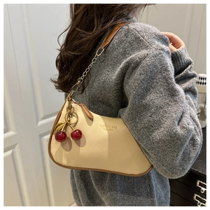 Détail du sac bandoulière tendance en beige et marron avec breloque cerise et cuir grainé