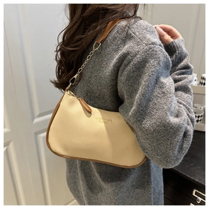Mannequin portant un sac hobo beige en cuir avec chaîne dorée et liseré marron