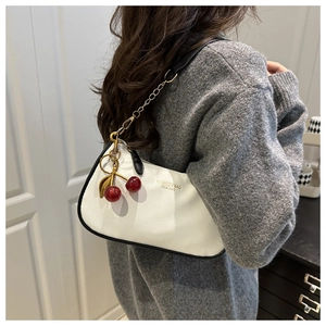 Detail of white litchi leather bag with black trim and 3D cherry charm attachment