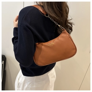 Gros plan sur un sac bandoulière en cuir marron grainé avec chaîne dorée et sangle
