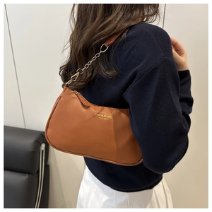 Détail d'un sac croissant en cuir marron avec bandoulière à chaîne dorée élégante