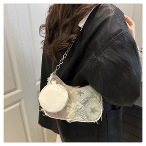 Détail du sac bandoulière en toile avec bords effilochés, étoile verte et chaîne argent