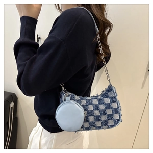 Detail of denim checkerboard shoulder bag with frayed edges and silver chain strap