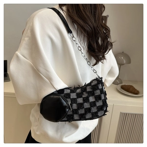 Detail of checkered denim shoulder bag featuring silver chain and round leather charm