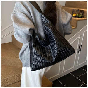 Detail of black woven leather tote bag showing large capacity and hobo shoulder strap style