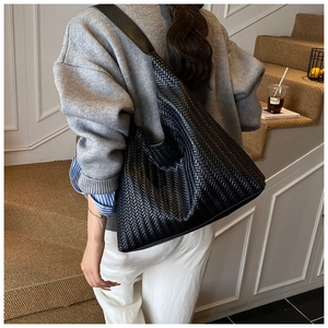 Detailed close-up of the woven leather texture and large capacity structure of the black hobo bag