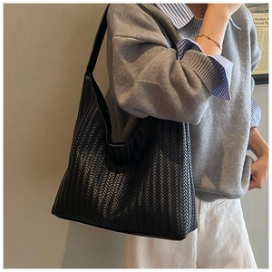 Detail of black woven hobo shoulder bag showing its large capacity on a model side view