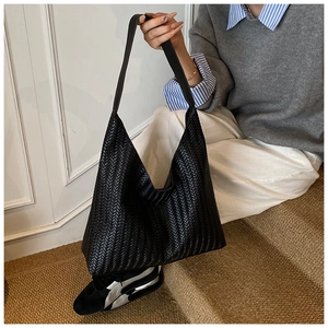 Detail of black woven hobo shoulder bag with intricate geometric texture and wide strap