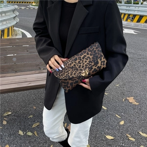 Leopard print envelope clutch with gold buckle shown in a stylish street style context