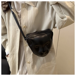 Détail d'un sac bandoulière noir avec relief 3D animalier porté sur un manteau
