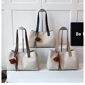 Close-up of canvas tote bags with leather handles and decorative plush bear charms
