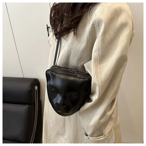 Détail du visage de léopard en relief 3D sur un sac bandoulière en cuir noir chic