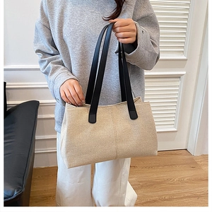 Detail of minimalist beige canvas tote bag with black handles in a casual setting