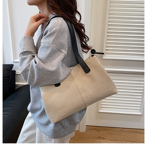 Detail of minimalist cream canvas tote bag with black leather straps and grain texture