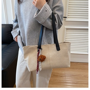 Detail of canvas tote bag with contrast leather handles and cute brown bear pendant