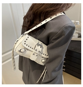 Macro shot of silver metal rivets and large buckle detail on the white punk style bag