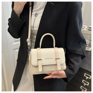 Détail du sac en cuir blanc cassé texturé avec boucles et inscription mode élégante