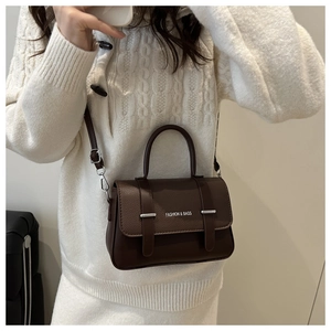 Detail of dark brown lychee texture leather handbag with silver metal hardware and strap