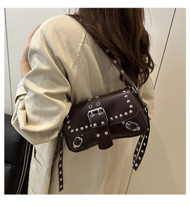 Detalle de un bolso baguette punk marrón oscuro con tachuelas plateadas en una modelo femenina