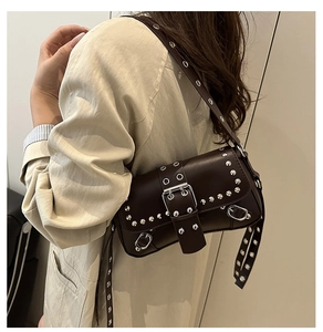 Detalle del bolso de hombro en cuero marrón oscuro con tachuelas en una modelo