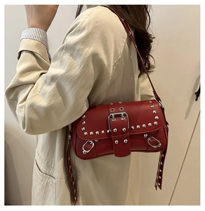 Detail of red punk shoulder bag featuring silver rivets and metal eyelet decorations
