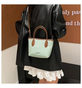 Détail du sac cabas en cuir vert menthe et marron avec logo FASHION et bandoulière