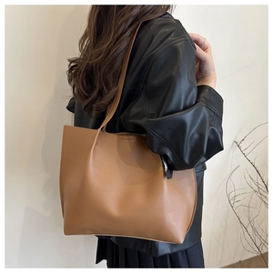 Brown faux leather tote bag with minimalist design shown on shoulder for daily commute