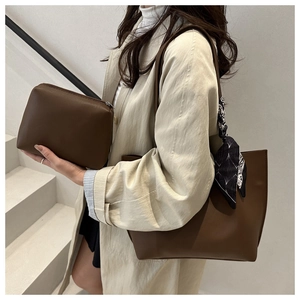 Brown bucket tote bag with decorative scarf and matching pouch held by a model