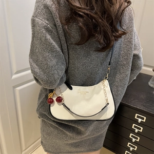 Sac bandoulière blanc en cuir grainé avec bordure noire et breloque cerise élégante