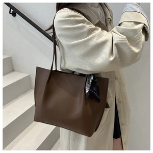 Detail of dark brown leather tote bag with printed silk scarf and slim shoulder straps