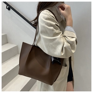 Deep brown large leather tote bag with stylish polka dot scarf on model in studio