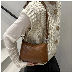 Detailed view of brown retro shoulder bag with knot strap detail and matte finish