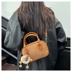 Sac bowling en daim marron avec pendentif en peluche porté par le modèle