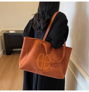 Detailed back view of a retro brown suede tote bag with double straps worn by a model