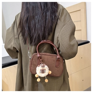 Détail du sac bowling vintage en daim marron avec breloque mouton sur blazer