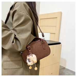 Sac bowling en daim marron avec bandoulière et pendentif mouton porté par un mannequin