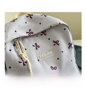 Vue détaillée du sac à dos violet avec motif nœud, étiquette et double fermeture