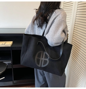 Detailed view of large black tote bag with BB logo shown on model for daily commuting
