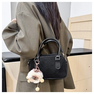 Détail du sac Boston noir mat avec pendentif mouton et poignées en cuir lisse
