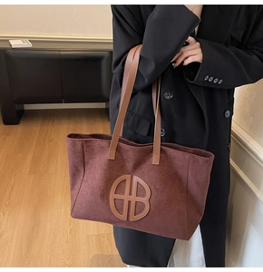 Detail of a large vintage burgundy tote bag with logo patch and brown shoulder strap