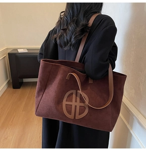 Macro shot of dark burgundy suede texture and premium leather logo patch on tote bag