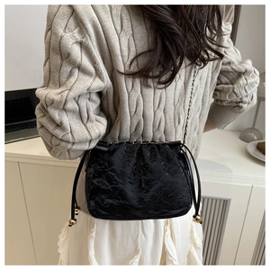 Détail du sac seau à cordon noir avec texture plissée et accents de billes dorées