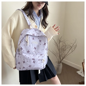 Détail d'un sac à dos violet à motifs de nœuds et étiquette Fashion pour étudiants