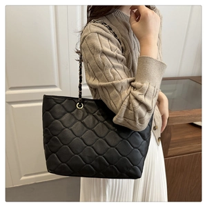 Detailansicht der schwarzen gesteppten Shopper-Tasche mit goldener Gliederkette und Leder