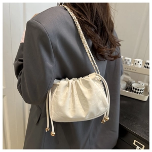 Détail d'un sac bourse blanc crème avec bandoulière chaîne en métal et pendentif doré