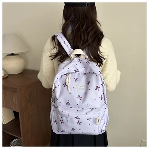 Détail d'un sac à dos d'école lavande avec motifs nœuds porté par un mannequin de dos