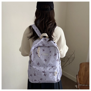 Détail d'un sac à dos lavande avec motifs de nœuds et poignée en sangle blanche robuste