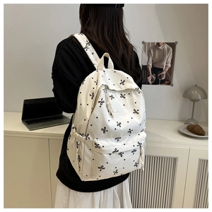 Détail d'un sac à dos en toile blanche avec nœuds noirs et étiquette mode sur la poche