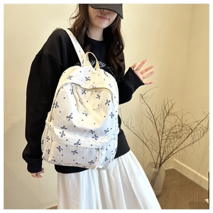 Détail d'un sac à dos blanc à imprimé nœuds bleus avec poche avant vue de côté