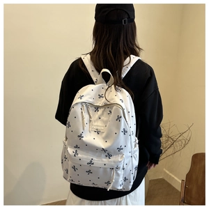 Détail du sac à dos en toile crème avec motifs nœuds noirs et étiquette FASHION